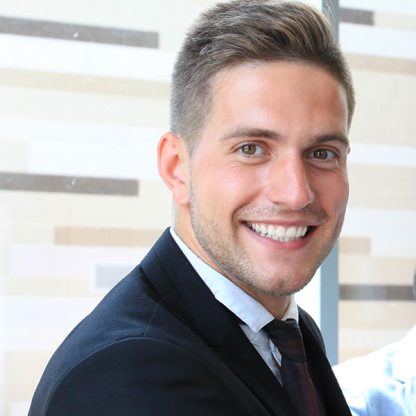 a man in a suit and tie smiling at the camera.